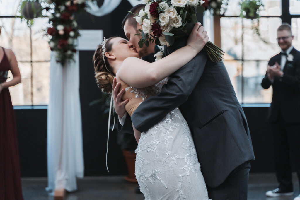 Jordan & Logan pausing for a kiss during the recessional at their wedding ceremony at Seventh Son Brewing Co in Columbus, OH