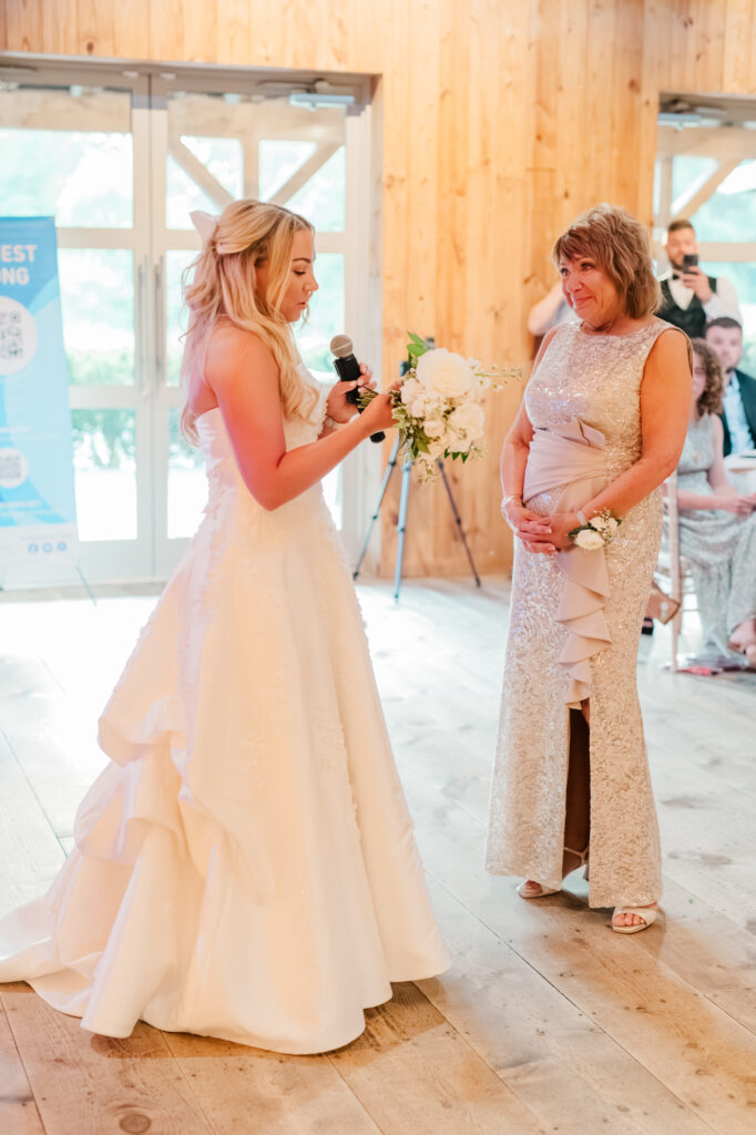 Anna presents her bouquet to her mom during her wedding reception inside the Historic Barn at Jorgensen Farms in Westerville, OH