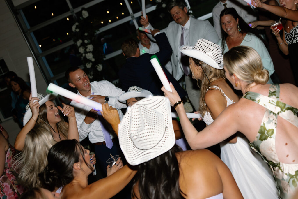 A packed wedding reception dance floor with light sticks in the air at Allison & Joe's Wedding Reception at Williams Farm in Pataskala, Ohio
