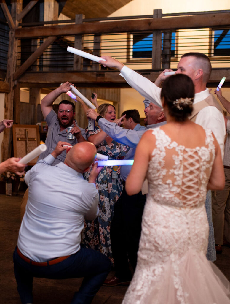 Light sticks in the air and guests dancing at Sarah & Ryan's Wedding Reception at The Old Barns at Dry Run Farms in Williamsport, Ohio