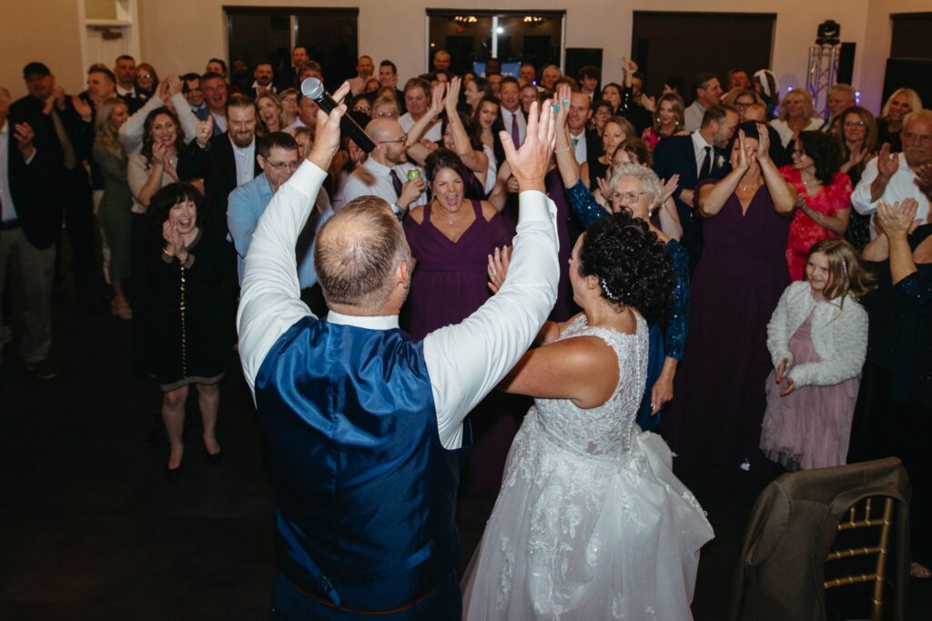 Heidi & Rusty sing along with their guests at their wedding reception inside the ballroom at The Wenbeck Wedding & Events Center